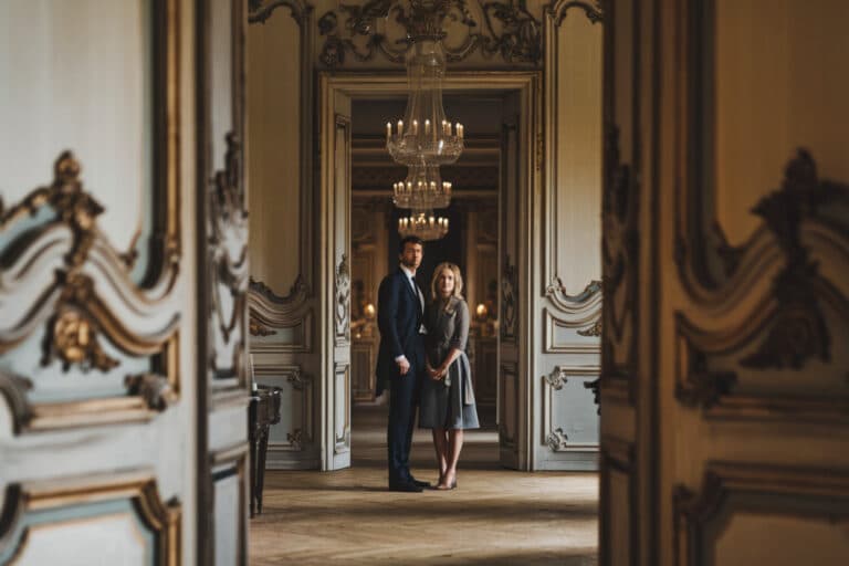 Couple posant fièrement dans leur château magnifiquement restauré avec ses pièces rénovées.